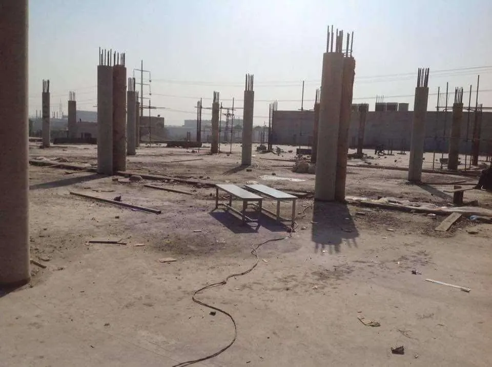 Reinforced concrete columns rising from a levelled factory site