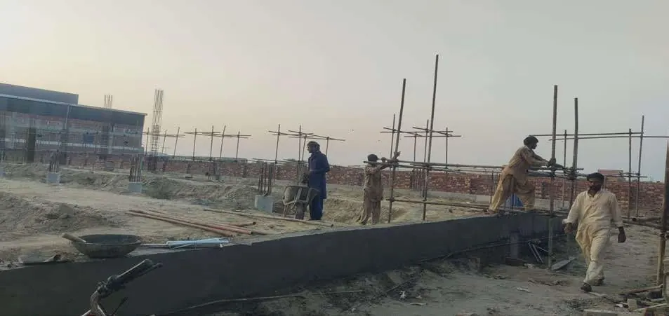 Construction crew working on a boundary wall beside an industrial building